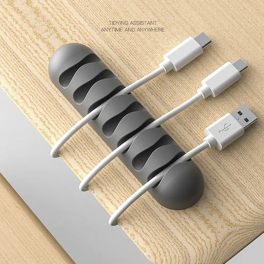 Smooth Design Silicone Cable Holder In grey on Wooden table with 3 white cables