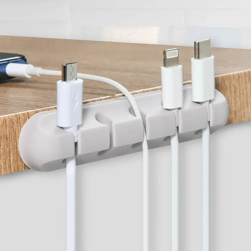 Scalloped Design Silicone Cable Organizer in white used at edge of table iwht cables and a smart phone